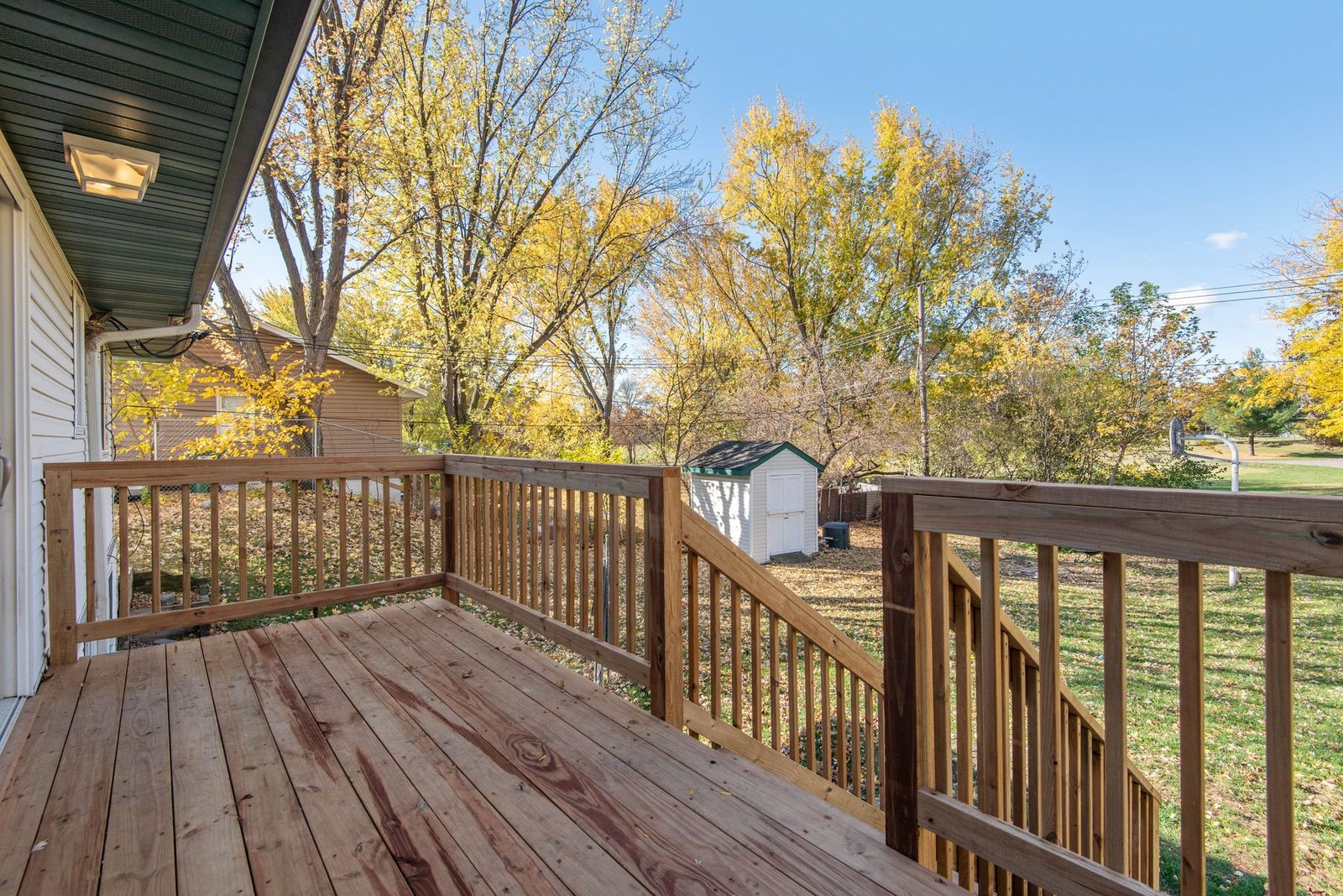 Wide wood deck overlooking a backyard in autumn