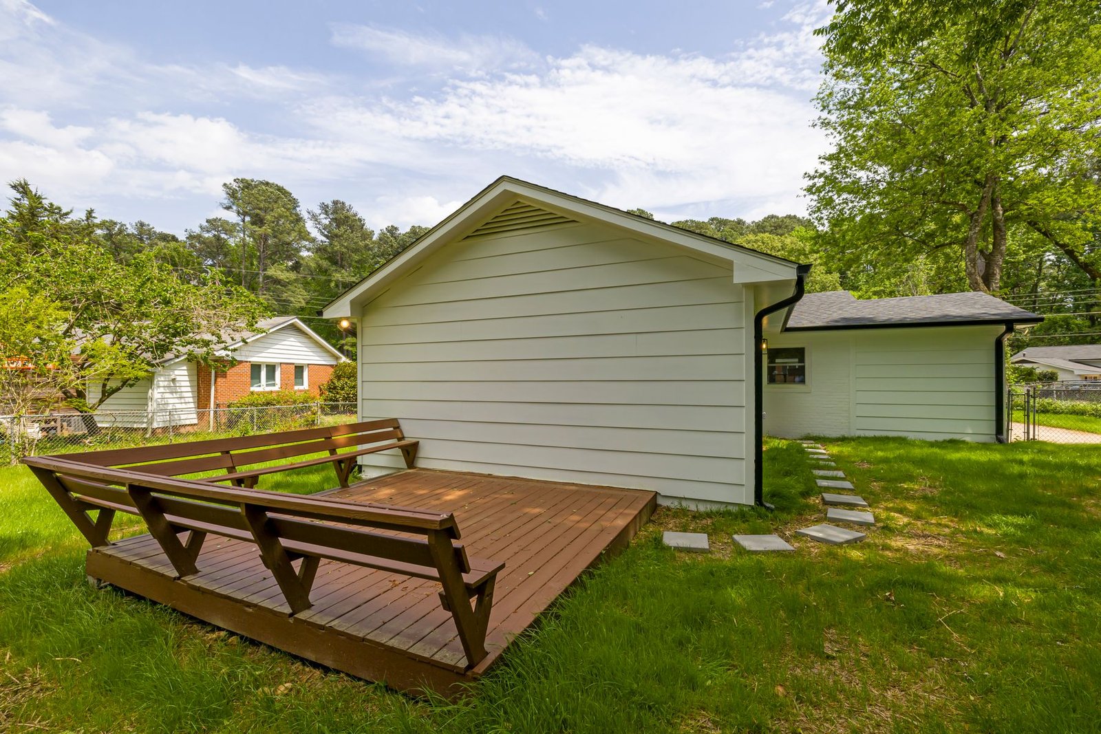 Backyard wood deck surrounded by greenery behind a house