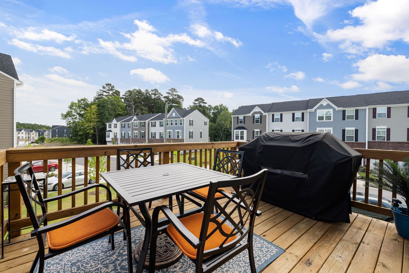 Wood deck with outdoor furniture and grill at the back of a suburban home