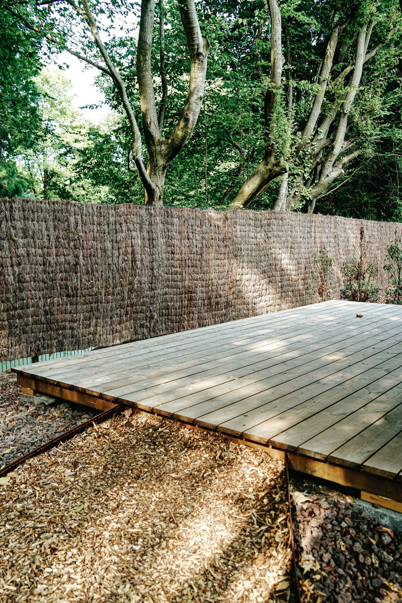 Wood deck enclosed by trees and a privacy fence