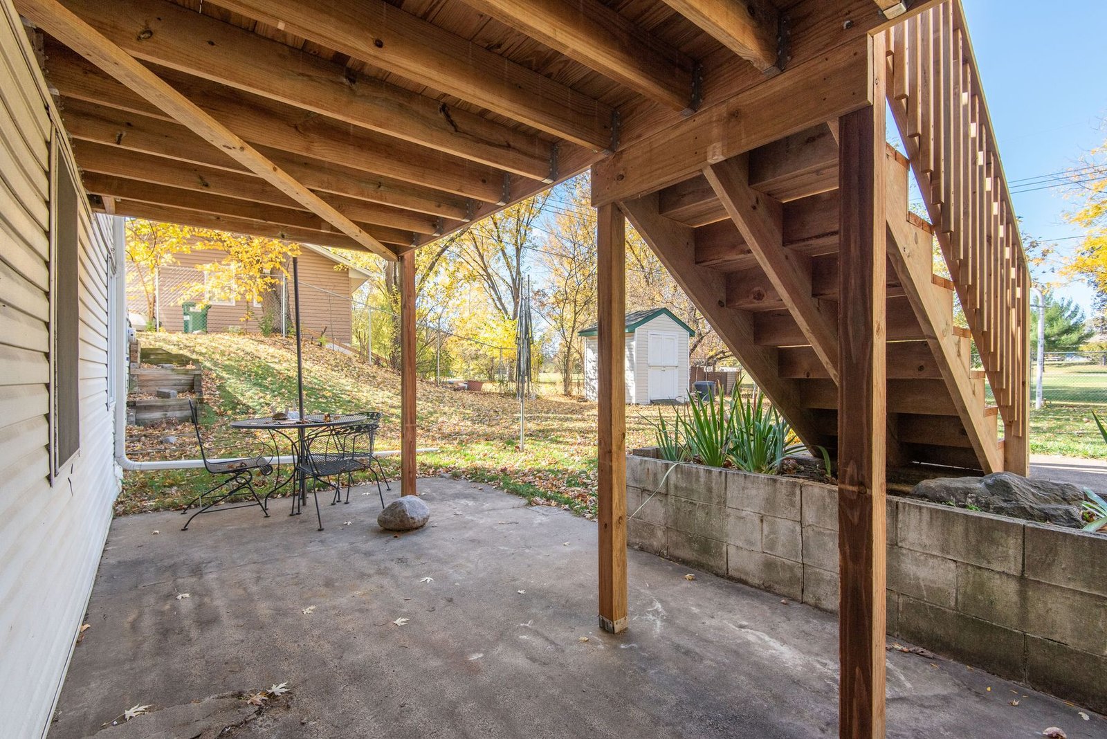 Wooden deck stairs leading down to a backyard patio